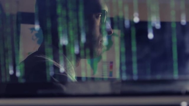 man working at a laptop in the reflection of the monitor