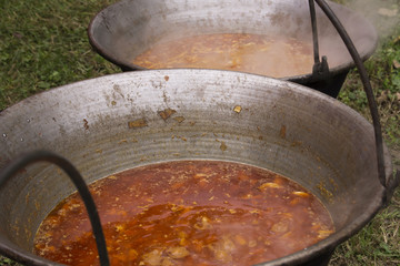 Traditional hungarian dish - bogracs goulash, stewed meat and vegetables in cauldron, outside in...