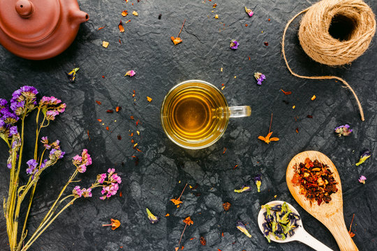 Flat lay with tea, herbs, dried flowers on black background