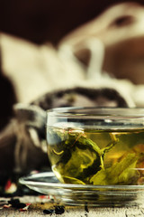 Green Ceylon tea in the cup, old wooden background, selective fo