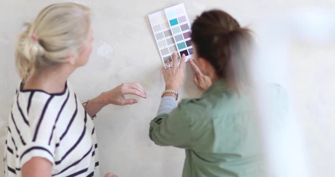Mature female friends looking at colour card