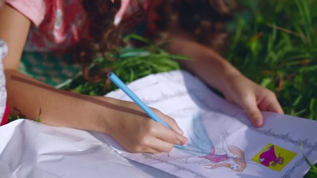 Little girl draws in the garden