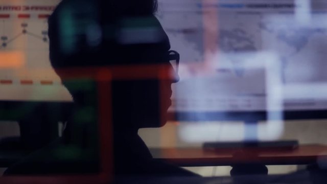 man working at a laptop in the reflection of the monitor