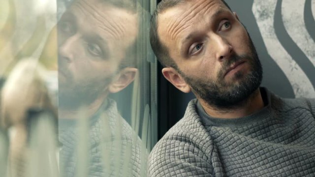 Sad, unhappy man sitting by window in cafe
