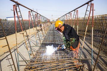 In the construction site, the welding workers at work - obrazy, fototapety, plakaty