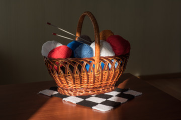 multicolored tangles lie to a basket with knitting needles and p