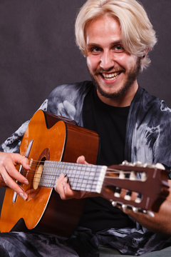 Blonde man playing acoustic guitar