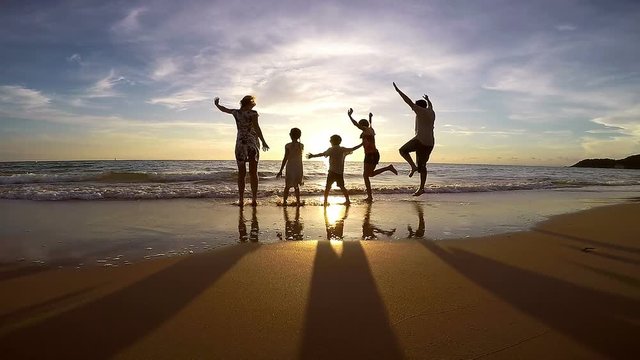 Silhouette of happy people who playing on the beach at the sunset time. Concept of friendly family. Video filmed on camera Gopro. 