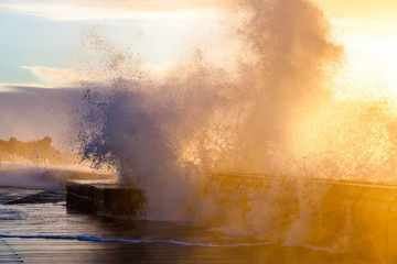 Huge waves crushing with force on Mornington Pier and Breakwater at sunset. Melbourne, Australia