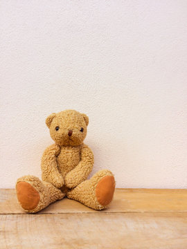 Brown teddy bear sit on the wooden floor.