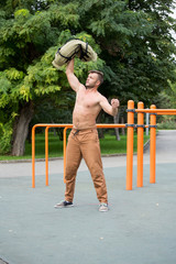 Fototapeta premium Man Performing Bag Squat Exercise Outdoor