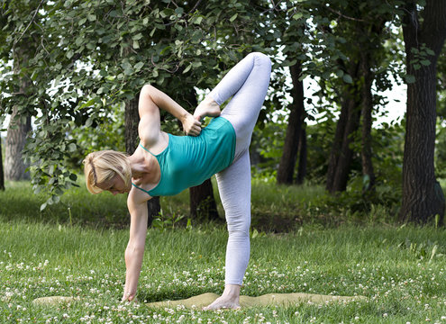 young blond woman doing yoga and gymnastics in the park