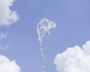 Naklejka na ściany i meble Fountain water splash against blurred sky with clouds, selective focus, shallow DOF.