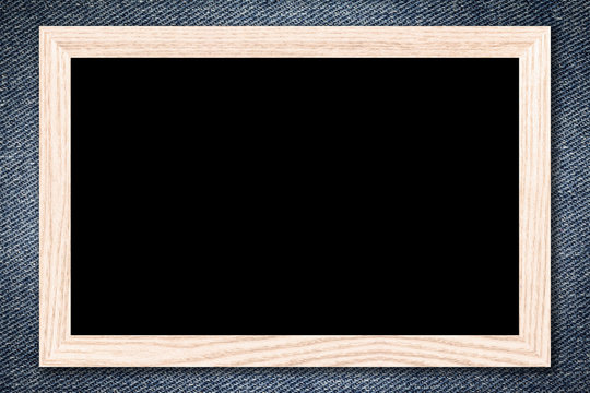 Blackboard or Empty bulletin board with a wooden frame on denim jeans background with copy space for text or image.