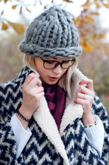 Student girl in  park wearing warm cardigan and knitted hat