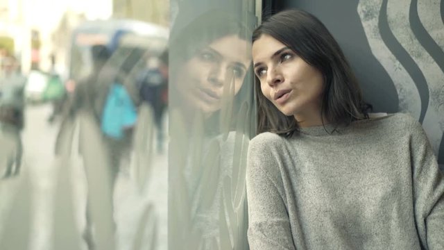Sad, unhappy woman sitting by window in cafe
