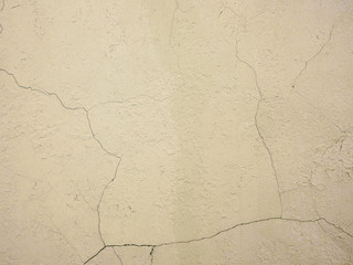 The old plastered background on a building wall with cracks and chips