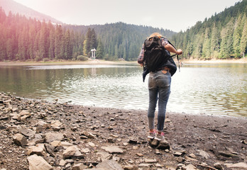 Young woman stands near a mountain lake enjoy the landscape