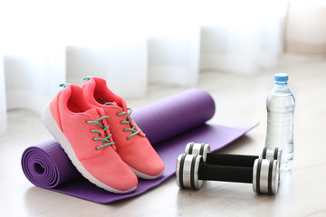 Comfortable sneakers with sport tools on floor