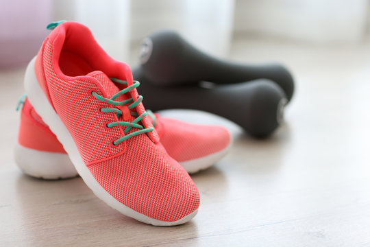 Comfortable sneakers with sport tools on floor