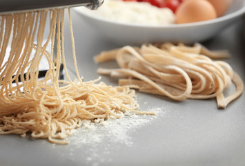 Making tagliatelle with pasta machine on kitchen table