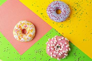 Tasty donuts with sprinkles on colorful background