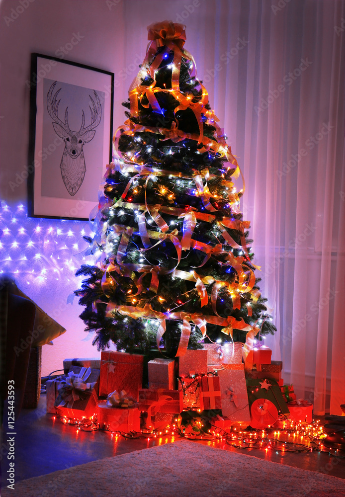 Poster decorated christmas tree and boxes with presents in living room