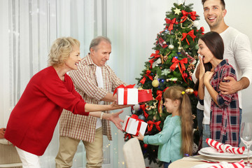 Obraz na płótnie Canvas Happy members of family giving Christmas presents to each other