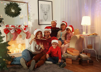 Family reading book in living room decorated for Christmas