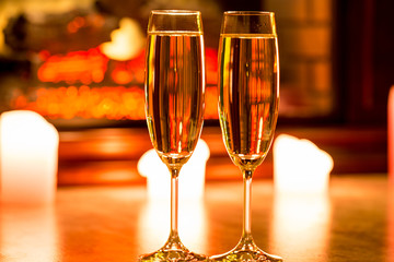 Beautiful two glasses of champagne standing on the table in the background of a blurred room with a decorated Christmas tree and candles. Soft focus. Shallow DOF