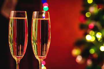 Beautiful two glasses of champagne standing on the table in the background of a blurred room with a decorated Christmas tree and fireplace. Soft focus. Shallow DOF