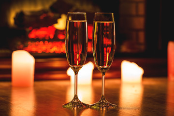 Beautiful two glasses of champagne standing on the table in the background of a blurred room with a decorated Christmas tree and candles. Soft focus. Shallow DOF