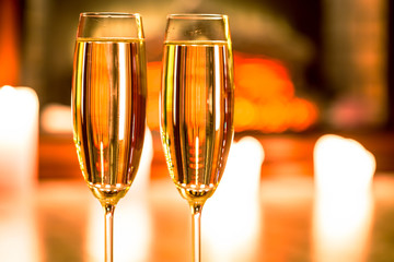 Beautiful two glasses of champagne standing on the table in the background of a blurred room with a decorated Christmas tree and candles. Soft focus. Shallow DOF