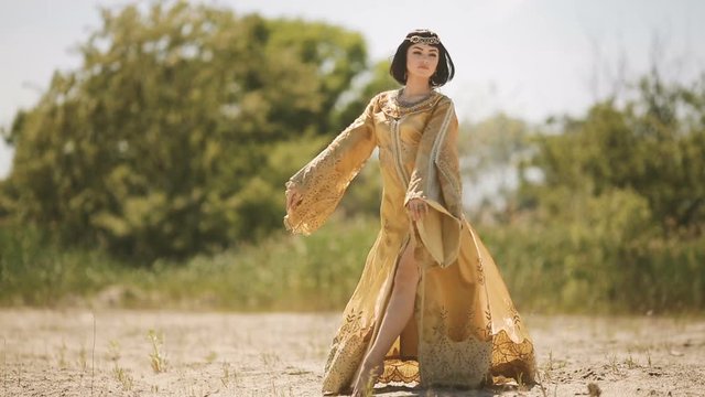 Beautiful woman like Egyptian Queen Cleopatra on in desert outdoor.
