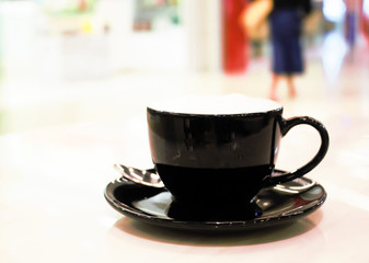 Hot coffee cup on abstract blurluxury shopping mall for background.