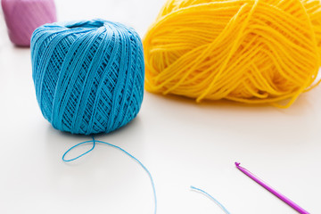 Bright colorful balls of yarn and crochet. Knitting equipment on white background, free space for text. Leisure, handiwork, hobby, handiwork concept