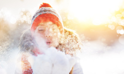 happy woman blowing snow in winter nature