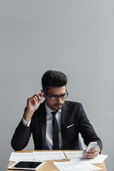 Businessman checking his phone and .papers on his desk