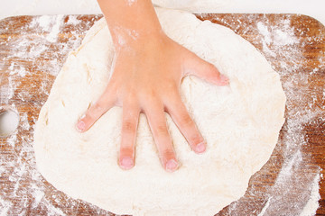 Kid making handprint on raw dough closeup. Child hand playing with pastry on kitchen. Homemade...