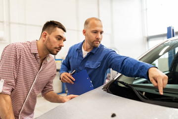 auto mechanic with clipboard and man at car shop