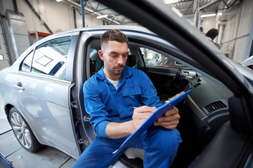 auto mechanic man with clipboard at car workshop