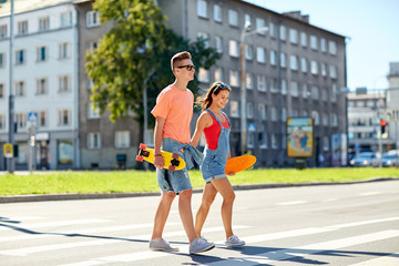 teenage couple with skateboards on city street