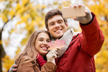 Fototapeta premium couple taking selfie by smartphone in autumn park