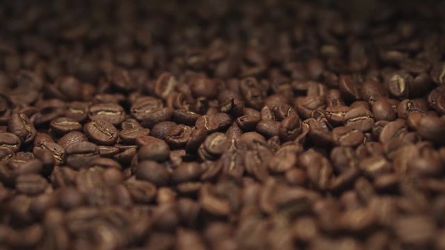 Amazing close up view of a big heap of fragrant brown coffee beans in a mixing roasting machine. Coffee making. No people around. International tastes. Inside shooting. Happy coffees day.