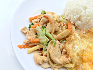 stir fry vegetables with chicken fillet, fried egg with rice in white dish on white background.