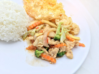 stir fry vegetables with chicken fillet, fried egg with rice in white dish on white background.