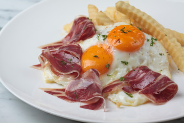 Appetizing Spanish Iberian cured ham with fried egg and chips on