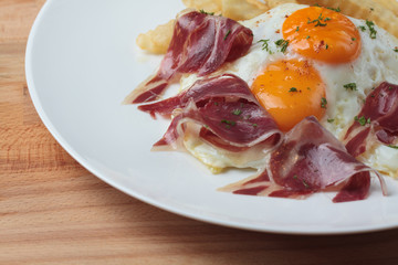 Appetizing Spanish Iberian cured ham with fried egg and chips on