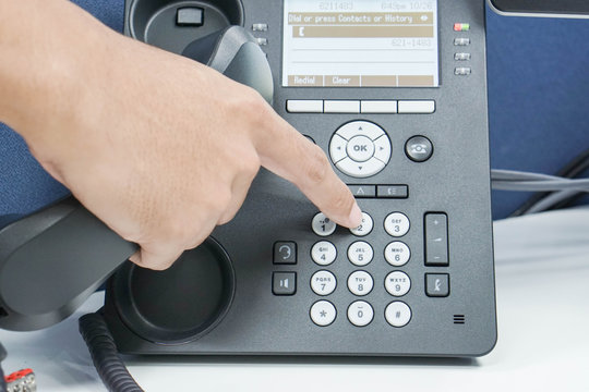 man dial numeric button of IP phone for calling