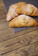 Freshly baked croissant pastries on a wooden breakfast table background forming a page border